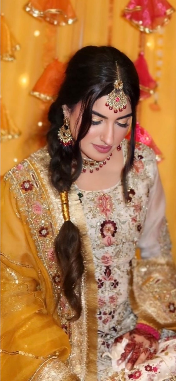 Soft bridal glam in gold with tikka and floral backdrop by Makeup by Nidari